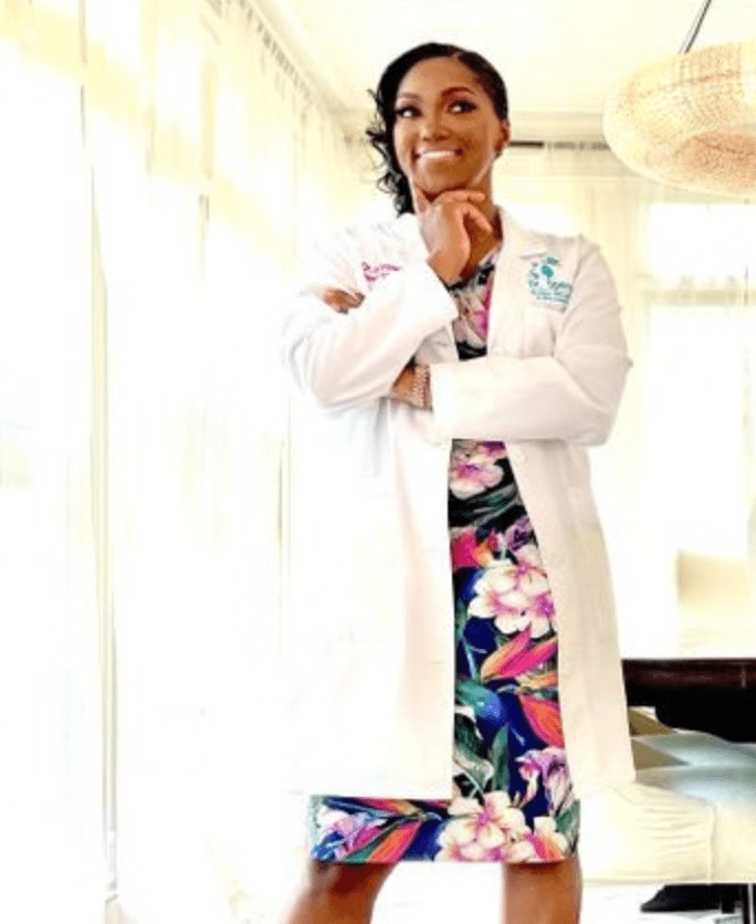 A woman in floral dress and white lab coat.