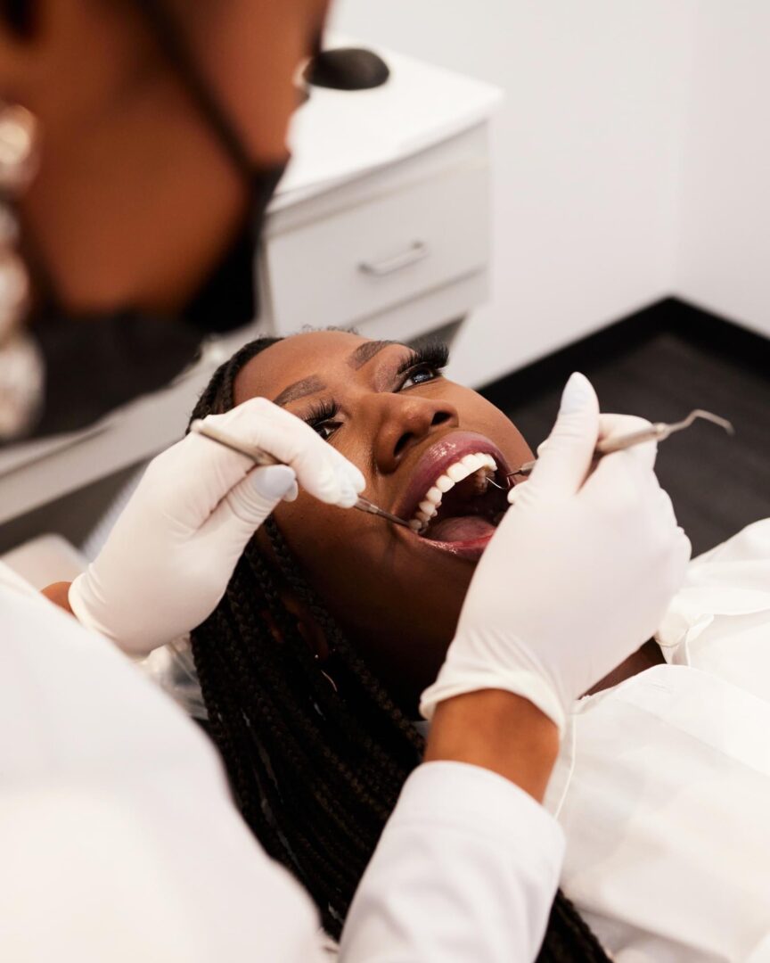 A woman is getting her teeth checked by an dentist.