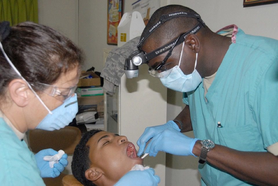 A dentist and his assistant performing an exam on a young patient.
