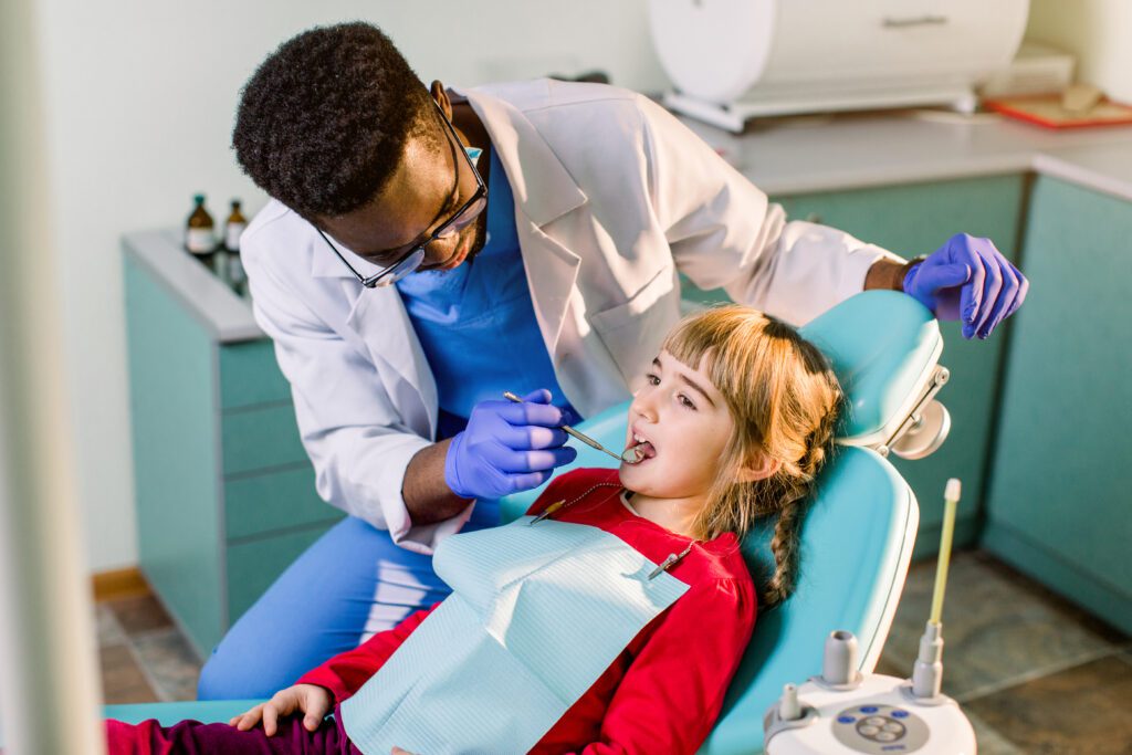 A dentist is examining the teeth of a young girl.
