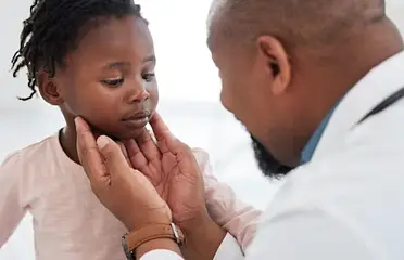 A doctor examining the ear of a young girl.