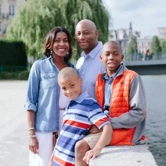 A family posing for the camera in front of some water.