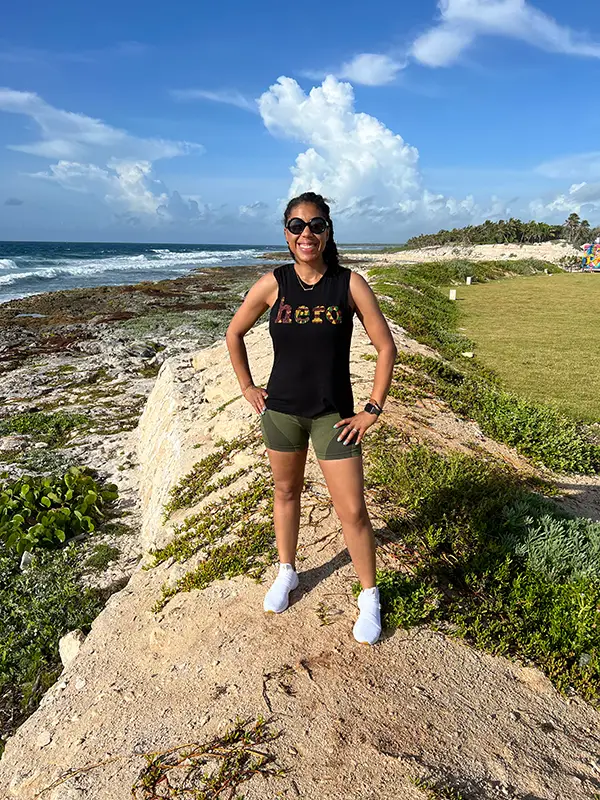 A woman standing on top of a hill near the ocean.