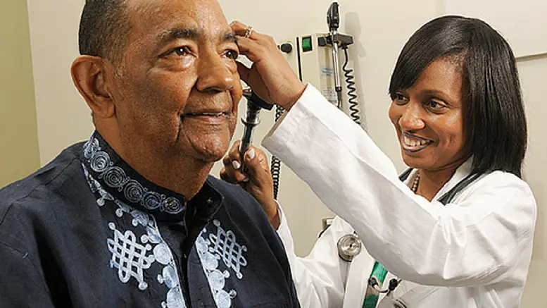 A doctor is checking the ear of an older man.