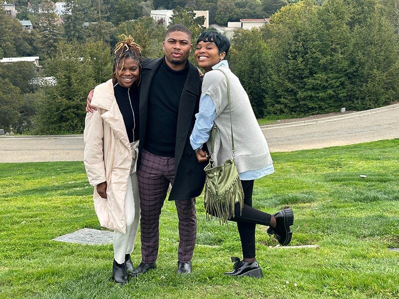 Three people posing for a picture in the grass.
