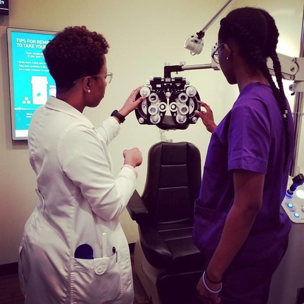 A woman and man in medical uniforms looking at an eye chart.